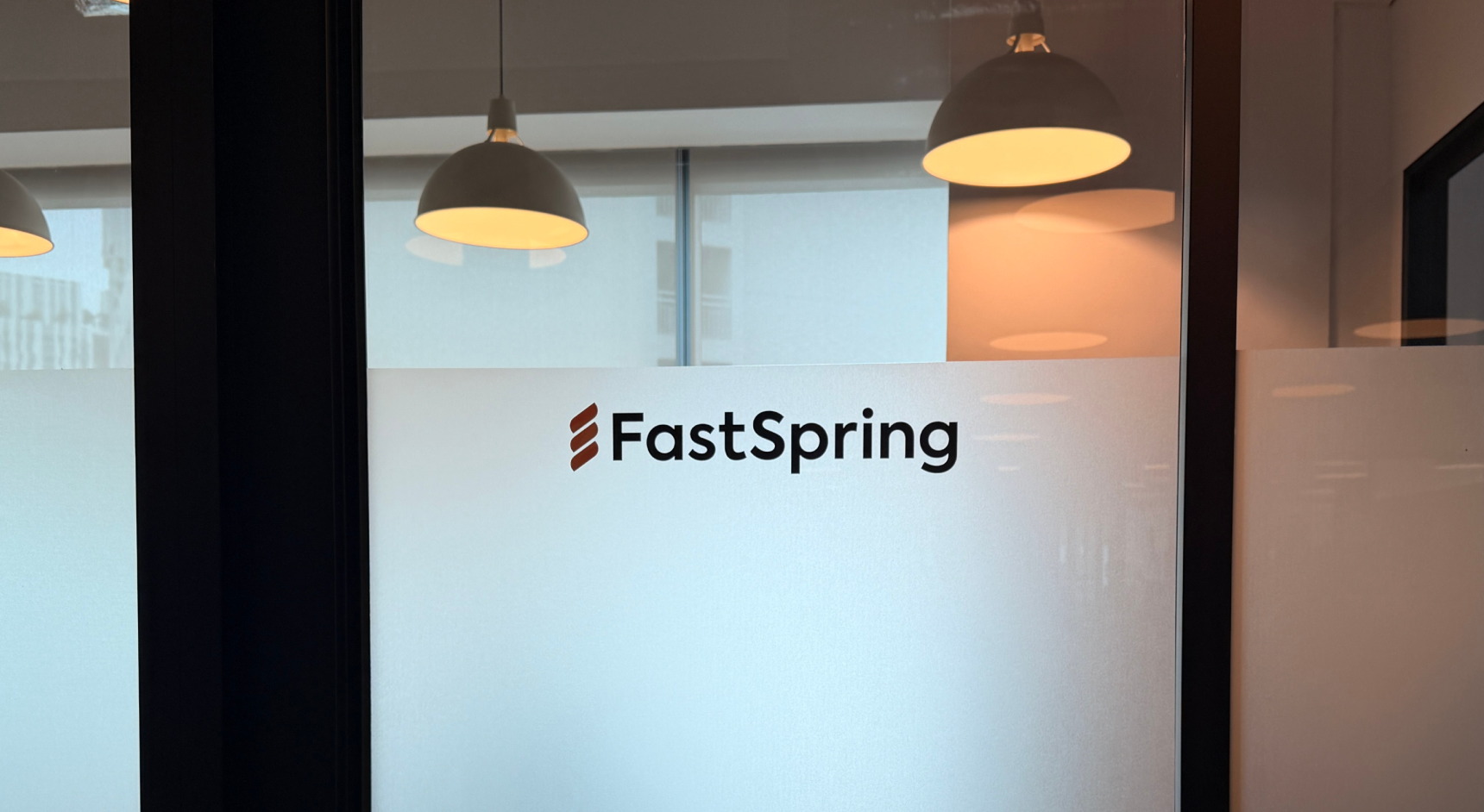 A frosted glass office door with the FastSpring logo on it.